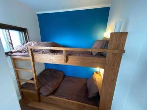 two bunk beds in a room with a blue wall at Poroto Base ウポポイまで徒歩2分 in Shiraoi