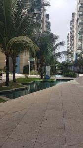 a swimming pool with palm trees in a city at Flat Beira Mar JTR Action in Maceió