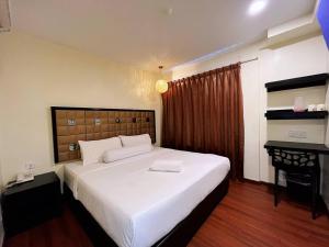 a bedroom with a large white bed and a desk at M Season Boutique Hotel Sdn Bhd in Sungai Petani