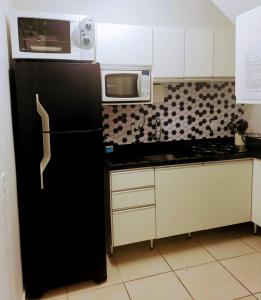 uma cozinha com um frigorífico preto e um micro-ondas em Residencial Catarina em Florianópolis