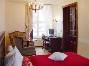a bedroom with a bed and a table and a desk at Hotel Altes Hafenhaus in Rostock