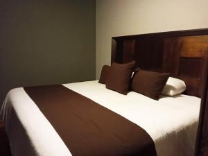 een slaapkamer met een groot bed met witte lakens en bruine kussens bij Hotel Suites La Fortuna in Mazamitla