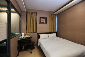 a hotel room with a bed and a desk and window at Shan-Yue Hotspring Hotel in Taipei