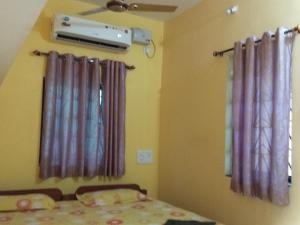 a bedroom with purple curtains and a bed and a fan at Casa De Olga in Vagator