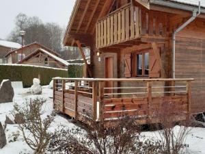 eine Holzhütte mit einer Veranda im Schnee in der Unterkunft Wooden chalet in Vosges by a pond in Zhezdi