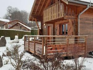 a wooden cabin with a porch in the snow at Wooden chalet in Vosges by a pond in Zhezdi