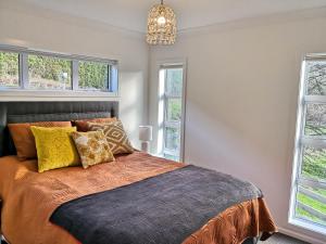 a bedroom with a bed and two windows at Karapiro Retreats holiday house in Cambridge