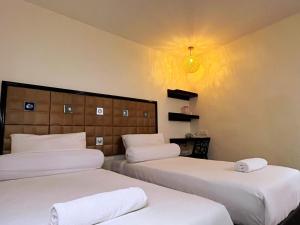 two beds in a hotel room with white sheets at M Season Boutique Hotel Sdn Bhd in Sungai Petani