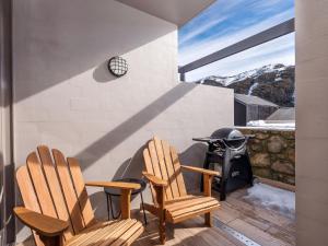 - deux chaises en bois assises sur une terrasse avec cheminée dans l'établissement KoKo Nanook Squatters 15, à Thredbo