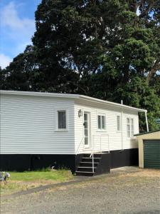 uma casa branca com uma garagem e uma árvore em Muriwai Lodge em Muriwai Beach