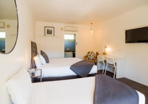 a bedroom with two beds and a desk and a television at Tower Motel Marysville in Marysville