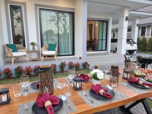 a wooden table with wine glasses and napkins at Baan Dalah Buriram in Buriram