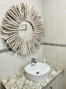 baño con lavabo y espejo en la pared en Tuscan House, en Hartenbos