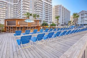 a row of blue chairs sitting on a wooden deck at Sea Watch Resort in Myrtle Beach