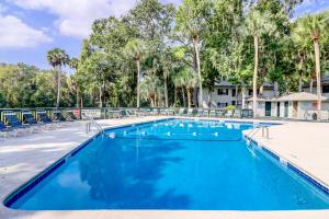 a swimming pool with chairs and palm trees at Harbour Master 103 in Hilton Head Island
