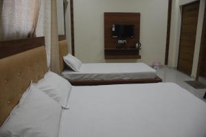a hotel room with two beds and a television at GURU KRIPA GARDEN in Govardhan