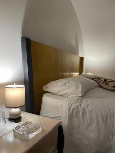 een slaapkamer met een bed en een tafel met een lamp bij Piccolo soggiorno ibleo in Ragusa
