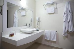 a bathroom with a sink, mirror, towel rack and towel dispenser at Gurkent Hotel in Ankara