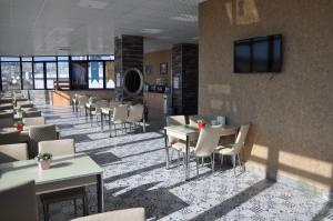 a restaurant with tables and chairs and a tv on a wall at ASİL OTEL in Urfa