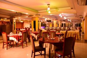 un comedor con mesas, sillas y mesa en Hotel Metro International, en Sylhet