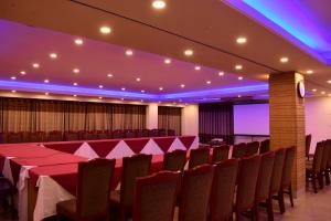 una sala de conferencias con mesas, sillas y luces púrpuras en Hotel Metro International, en Sylhet