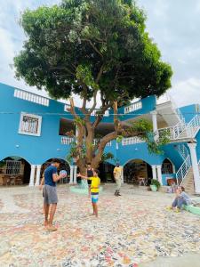 Un groupe de personnes debout autour d'un arbre sur la plage dans l'établissement Bajo Kunda - Guesthouse, à Kololi