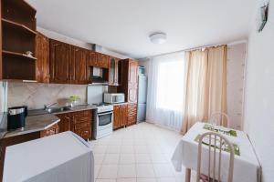 a kitchen with wooden cabinets and a table with a white counter top at Dekabrist Apartment on Chkalova 25 in Chita