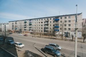 a street with cars parked in front of a large building at Dekabrist Apartment on Chkalova 25 in Chita
