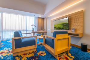 マジャレンカにあるHotel Horison Ultima Kertajatiの椅子2脚とテレビが備わるホテルルームです。