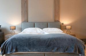 a large bed with a blue blanket and two lamps at Wyna Motel in Neudorf