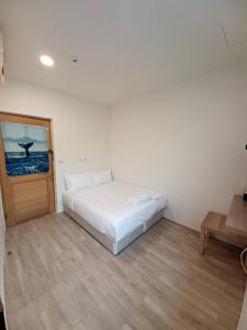 a bedroom with a white bed and a wooden floor at Kenting Ocean World Diving II in Hengchun