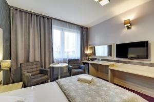 Pokój hotelowy z łóżkiem, krzesłami i telewizorem w obiekcie POKOJE GOŚCINNE MAC-TUR w Gdańsku