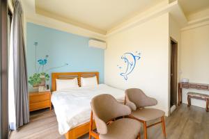 1 dormitorio con 1 cama y 2 sillas en Fengxianlu Herb Garden Homestay, en Magong