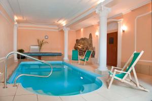 a swimming pool in a room with chairs and a table at Hotel Restauracja Kwisa 1 in Świeradów-Zdrój