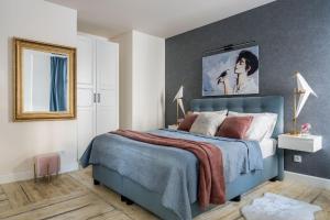 ソポトにあるSanhaus Apartments - Apartamenty Toledo - 3 minuty od plażyのベッドルーム1室(壁に絵画が描かれた青いベッド1台付)