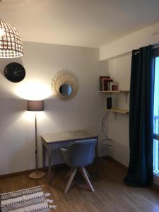 einen Schreibtisch mit einem Stuhl und einer Lampe in einem Zimmer in der Unterkunft Lumineux Studio 30m² sur Cour - Proche Tram/Centre in Nantes