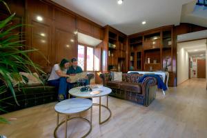 two people sitting on a couch in a living room at Dùplex Argollas Grand Suite Centro Parking gratis in Plasencia