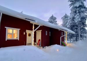 una casa roja con nieve a un lado. en Herranterttu Apartments, en Saariselkä