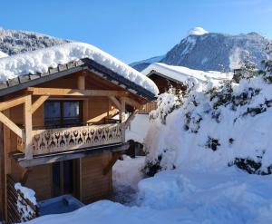 a log cabin with a balcony in the snow at Chalet Delphinette - Spa privatif in Morzine
