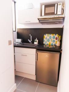 una pequeña cocina con fregadero y microondas en Studio Premium Zénith Arènes Purpan en Toulouse