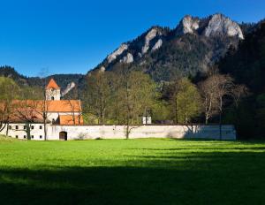 a building in a field in front of a mountain at Múzeum Červený Kláštor in Červený Kláštor