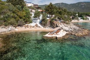 un grupo de tumbonas en el agua en una playa en Villa Romantica Hotel en PalaiónTsiflíkion