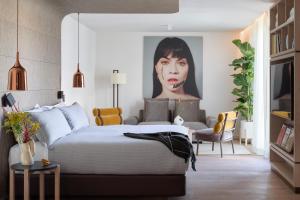 a bedroom with a bed and a painting of a woman at ME Barcelona in Barcelona