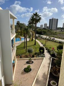 a balcony of a building with a pool and palm trees at Vila Praia 7 - Beach & Pool apartment in Alvor