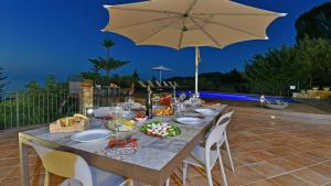 een tafel met eten en een parasol op een patio bij VILLA PROVENZA 12&4, Emma Villas in Cefalù