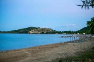 a beach with umbrellas and a castle on a hill at Stella boutigue rooms in Néa Péramos