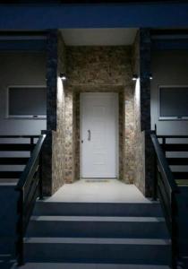 eine weiße Tür in einem Backsteingebäude mit Treppen in der Unterkunft Stella boutigue rooms in Néa Péramos