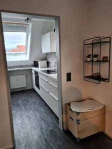 a small kitchen with white cabinets and a window at Maisonette-Wohnung mit Balkon in Radolfzell am Bodensee