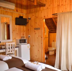 a bedroom with wooden walls and a kitchen with a refrigerator at Gecko Cottage Guesthouse in Prieska
