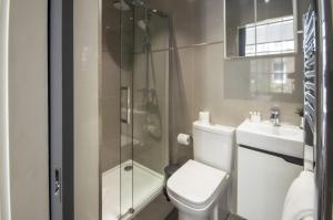 a bathroom with a toilet and a glass shower at High Street Kensington by Viridian Apartments in London